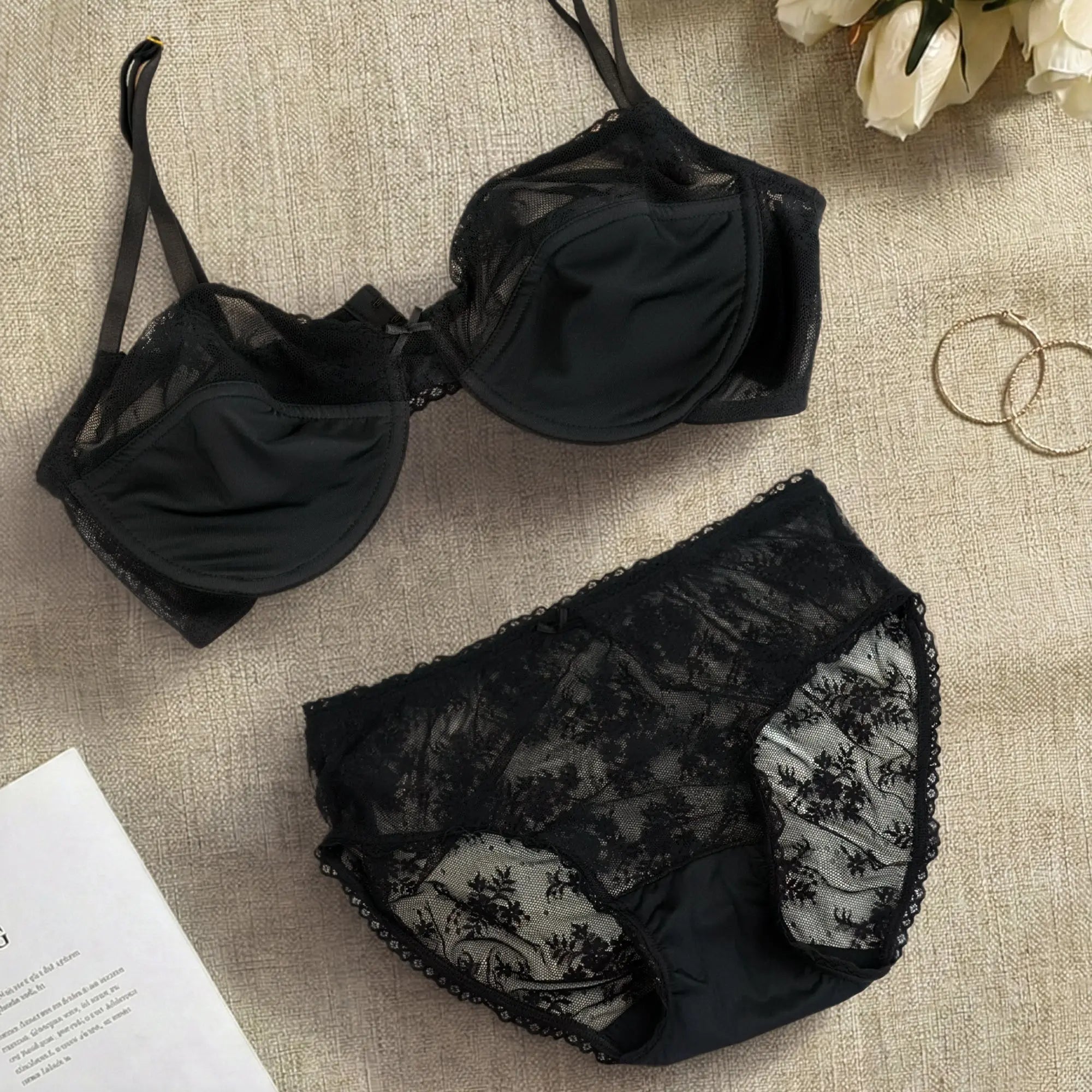 Black lace bra and panties set on a textured surface.