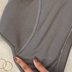 Charmella Period Panty with a hand touching the fabric on a textured surface