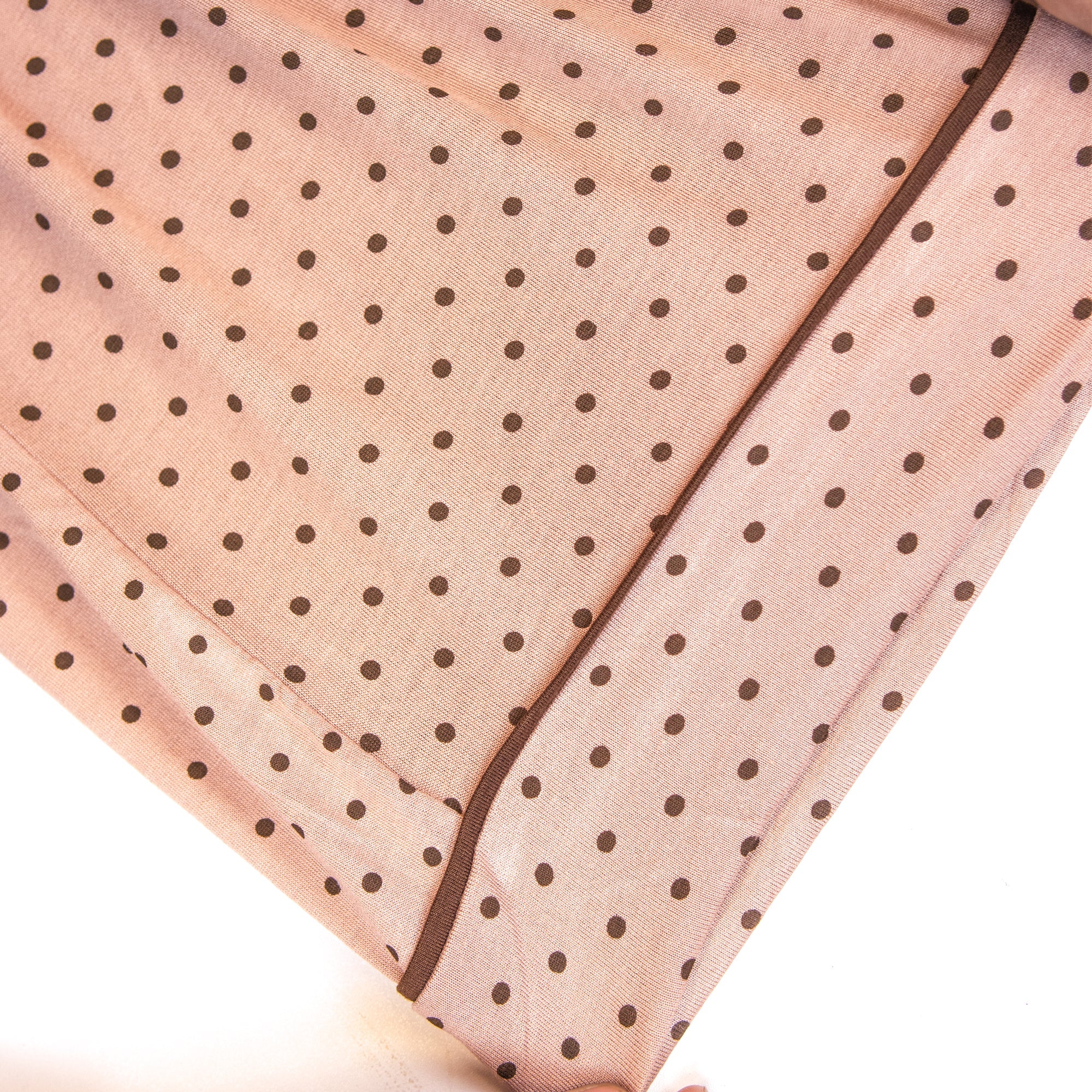 Pink pj set's fabric with black polka dots on a white background