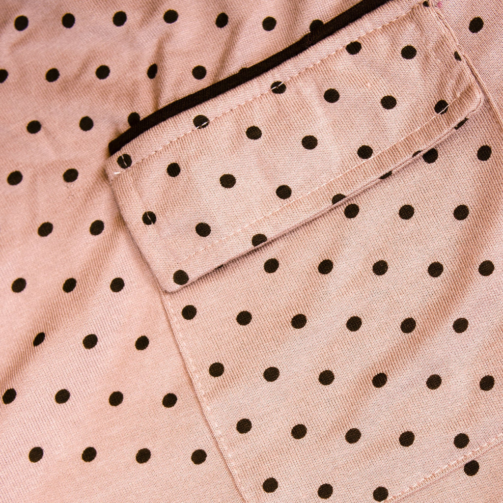 Close-up of a pink pj set fabric with black polka dots and a pocket.