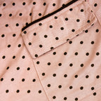 Close-up of a pink pj set fabric with black polka dots and a pocket.