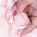 Close-up of a hand holding a Charmella Slip-On Bra fabric with a textured pattern.