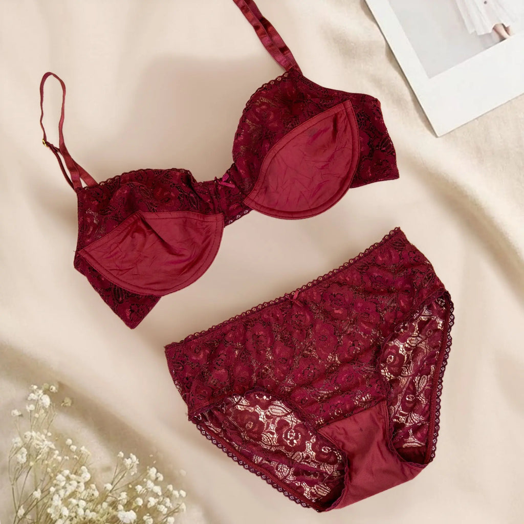 Red lace lingerie set on a beige surface with white flowers.
