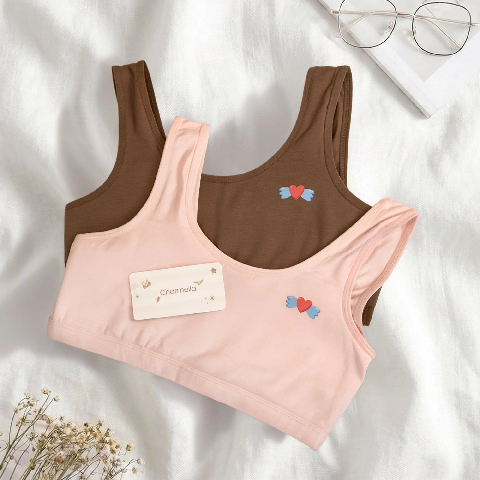 Two sports bras, one pink and one brown, with heart designs on a light background.